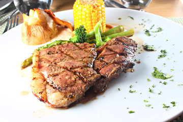 Sirloin steak served with vegetables on a white plate, shallow focus
