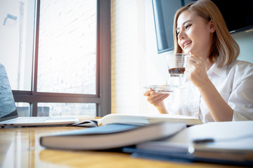 young businesswoman working with mobile phone laptop and holding coffee cup in office, business concept