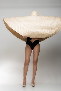 Asian Beautiful tan skin woman in Fashion black Swimwear stand on high heel shoes wear very big hat straw, studio lighting white gray backgrounds, copy space for text logo
