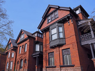 row of red brick Victorian houses with scalloped shingle pattern on gable