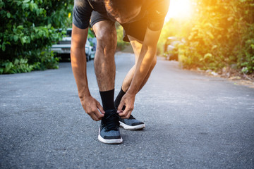 Men are binding shoes before jogging.Man running on street in the city park