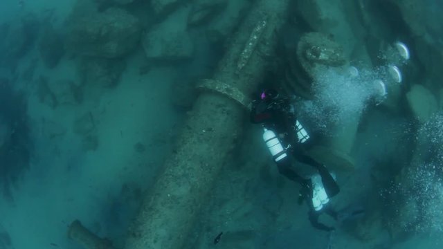 Scuba divers exploring an underwater pipeline sitting on the bottom of the ocean