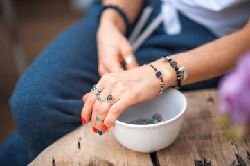 The hands of the girl touch the handmade jewelry. Girl and jewelry. Handmade woman decorating stones close up.
