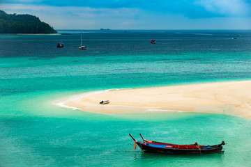 Fototapeta na wymiar Beach that extends into the sea Looking out to see the island And blue sky There are many boats floating in the emerald green sea of the Andaman Sea. At Sunrise Beach, Koh Lipe, Satun, Thailand