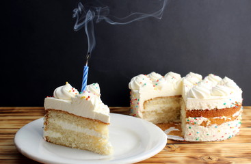 A piece of cake with white cream and an extinct single candle