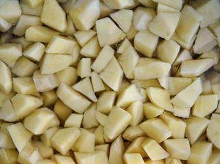 Potatoes cut in pieces in water.