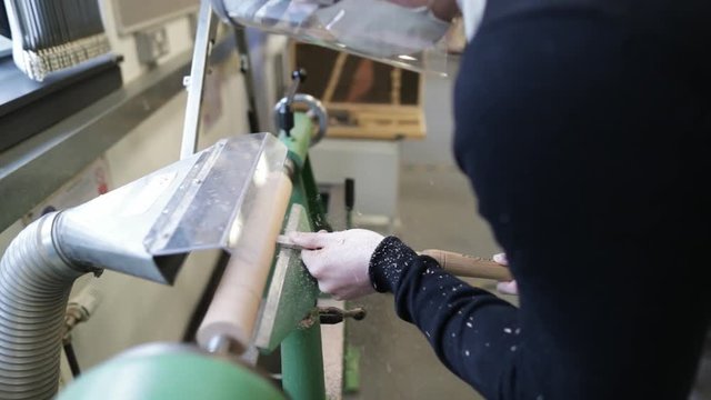 Woodworker uses a lathe machine to file wood (slow motion and from left hand  side)