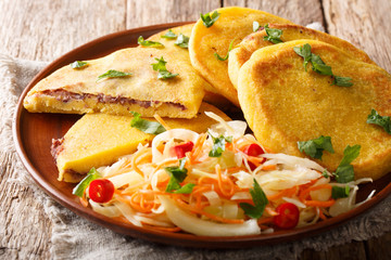 Delicious vegetarian fried Pupusas served with coleslaw close-up on a plate. horizontal