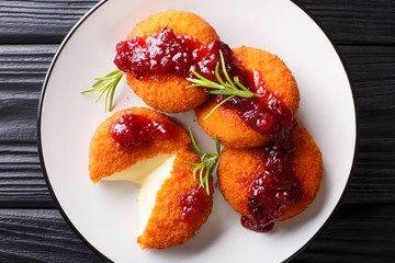 Gourmet appetizer Camembert in breading served with cranberry sauce and rosemary close-up on a plate. horizontal top view