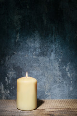 Single candle and dramatic lighting on grey stone background