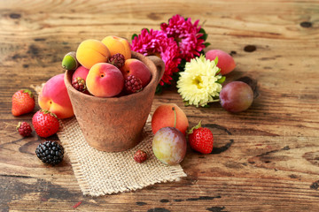 Ceramic bowl with various fruits. Wooden background.