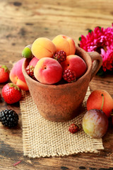 Ceramic bowl with various fruits. Wooden background.