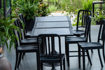 A table and a wooden chair placed in front of the balcony in cafe. Blurred and soft focus.