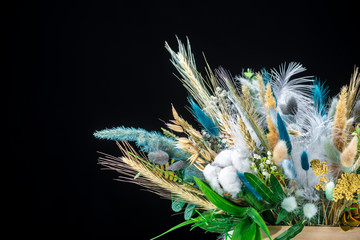 wooden box with beautiful spring floral bouquet decorated with feathers on black background 