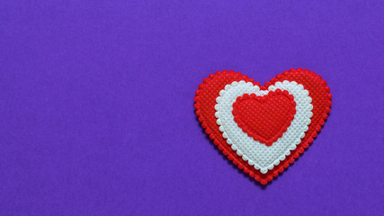 Bright red and white heart on purple background. The view from the top. Flat lay.