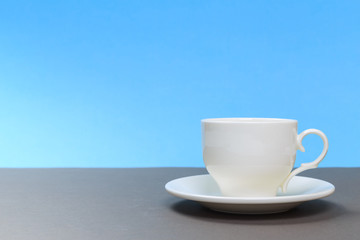 vintage white porcelain tea cup on gray board and blue background