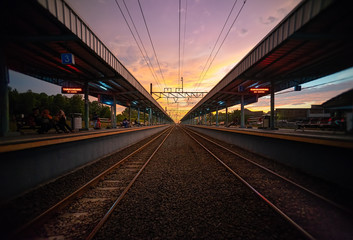 Fototapeta na wymiar Tigaraksa KRL Commuter Line Train Station at Sunset with Two Line of Railroad or Railway.