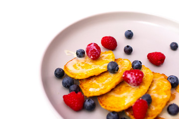 Fritters with berries on a plate on a white background