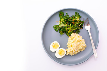 Millet porridge with salad and eggs on a plate on a white background