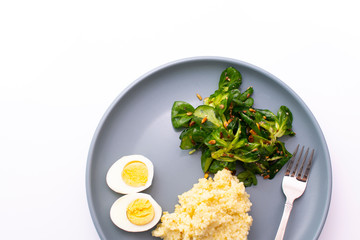 Millet porridge with salad and eggs on a plate on a white background
