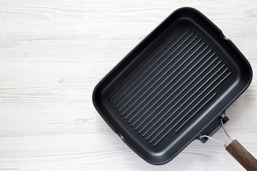 Empty grill pan on a white wooden background, top view. Overhead, from above, flat lay. Copy space.
