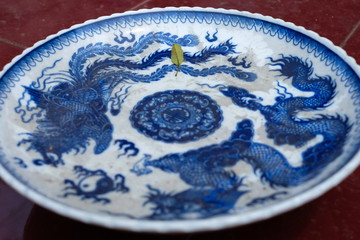 yin-yang balance and dragons blue ceramic plate and a green lead - close up