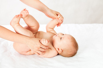 the baby trains the muscles of the hands holding and pulling up. masseuse doing massage baby. baby on white isolated background.