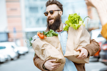 Happy stylish man with shopping bags full of fresh and healthy food outdoors near the supermarket