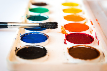 The palette of watercolor paint and one brush.Selective focus. Shallow DOF