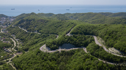 Fototapeta na wymiar Curvy windy road between green mountain forest, top down aerial view. Summer landscape.