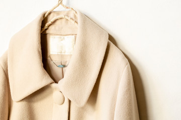 白バックにベージュのコートの肩や襟のクローズアップ