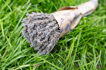 Lavender bouquet in paper packaging lying on the green grass. Horizontal orientation. Copy space. 