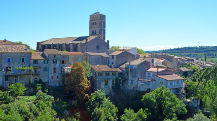 Obraz premium A view of the village of Montolieu Aude Languedoc - Roussillon France. Trees valley ancient houses and church bell tower.
