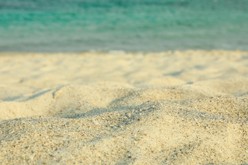 Fototapeta na wymiar Sea sand against blue sea water, space for text. Summer backdrop