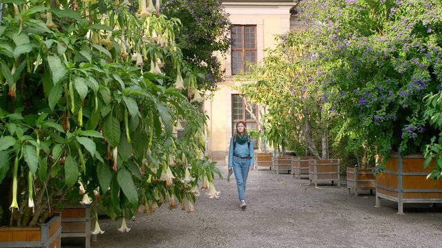 Hannover, Germany. A young female tourist with a map in her hands and a backpack walks around the aquarium with unusual trees that grow in huge wooden vases on which flowers grow. Looks