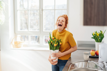 Young woman laughing holding a vase of tulips
