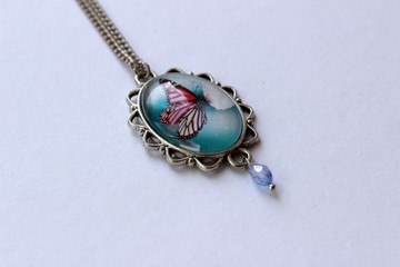 metal pendant with a butterfly under the glass on white background