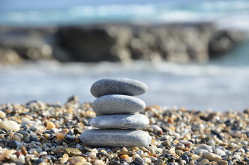 Zen pyramid of spa stones on the blurred sea background. Sand on a beach. Sea shores. Water waves texture. Place for text. concept of balance and spirituality