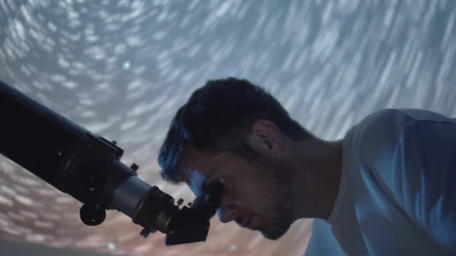 Amateur astronomer using telescope optics at night to look at gleaming sky stars