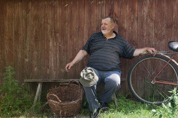 Ukrainian senior farmer sitting on a bench and smiling at summer day