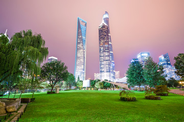 Obraz premium Of tall buildings in the center of the garden green space in the evening.