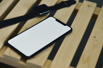Fototapeta premium Smartphones are big part of our daily life now. New generation smartphone with blank white screen for Infographic Global Business Marketing investment Plan. The cellphone is on wooden table.