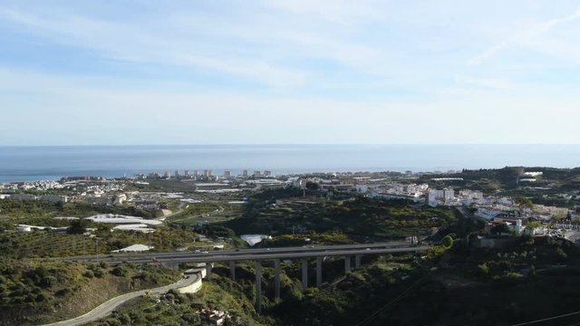 Cars circulating by a bridge in a highway with the sea and coast buildings