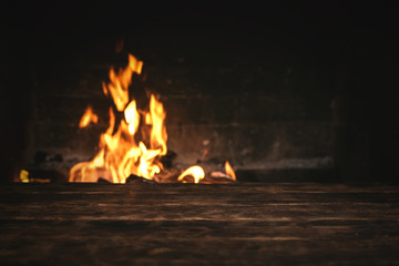 Empty table with a copy space for food for example over a burning fire in a brick fireplace.