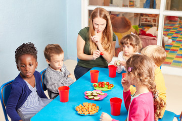 Erzieherin zusammen mit Kindern beim Essen