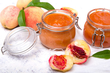 Homemade peach jam with organic fruit. Sweet preserves on a light background
