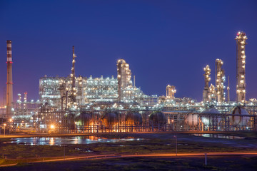 Fototapeta premium Oil refineries and oil depots and close-up of pipelines and destillation tanks of an oil-refinery plant in the evening