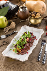 Meat Carpaccio with Salad and tomatoes on wooden table
