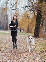 Young girl with dog running at the forest