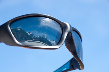 sunglasses reflecting mountains covered of snow in winter, alps